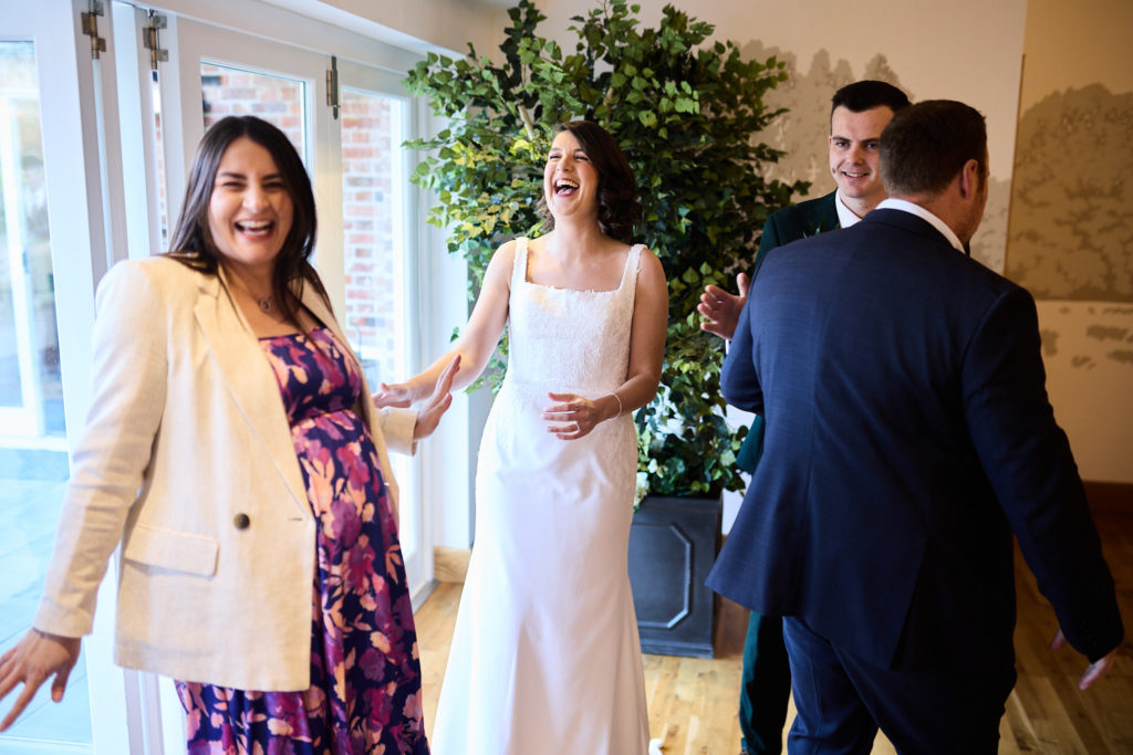Bride laughing with a guest as the groom looks on