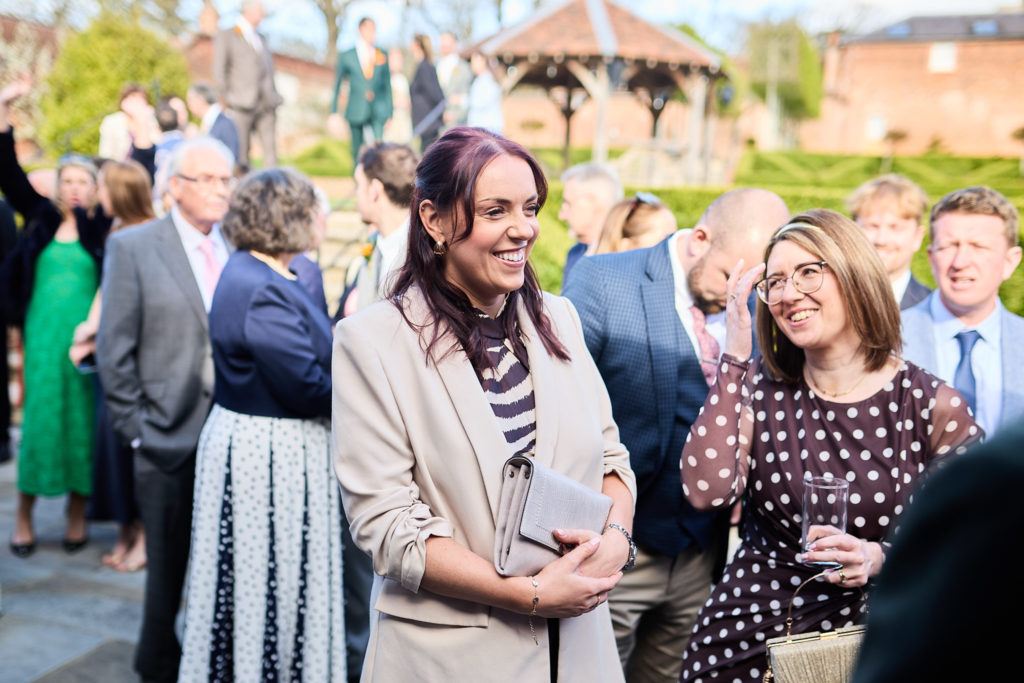 Wedding guests laughing together in the evening sun