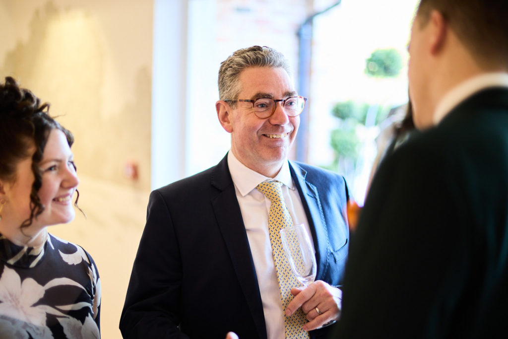 Wedding guest in glasses smiling during a conversation
