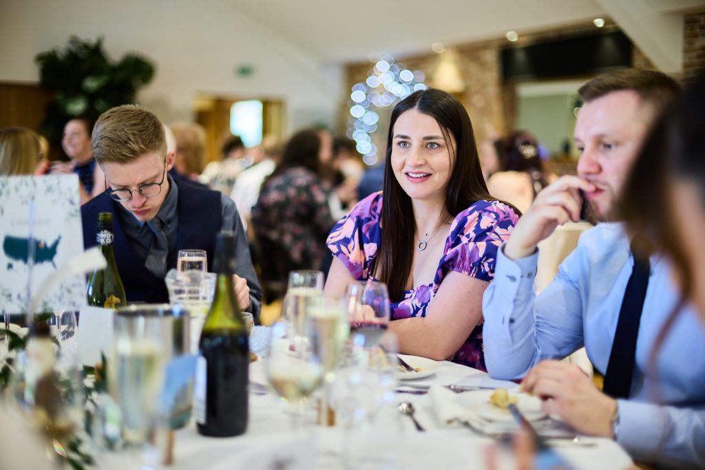 Wedding guests smiling at their table during the wedding breakfast