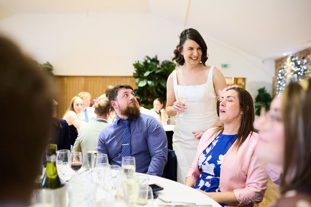 Woman standing to speak among seated wedding guests