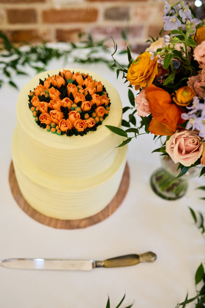 Wedding cake topped with orange roses, seen from above with a cake knife