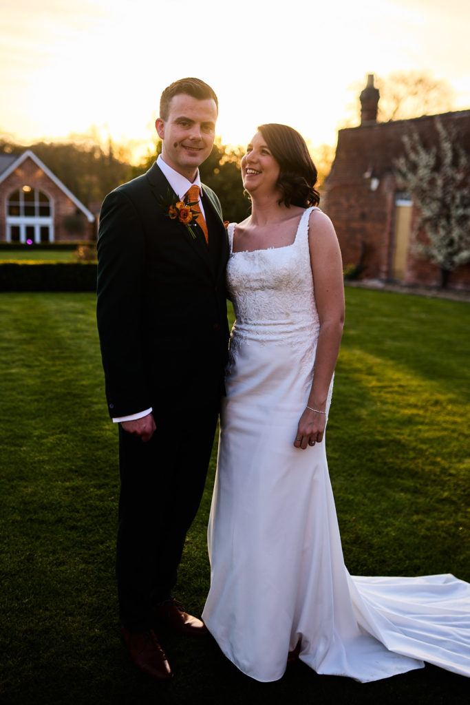 Bride and groom standing together on the lawn at Hatfield Place in evening light