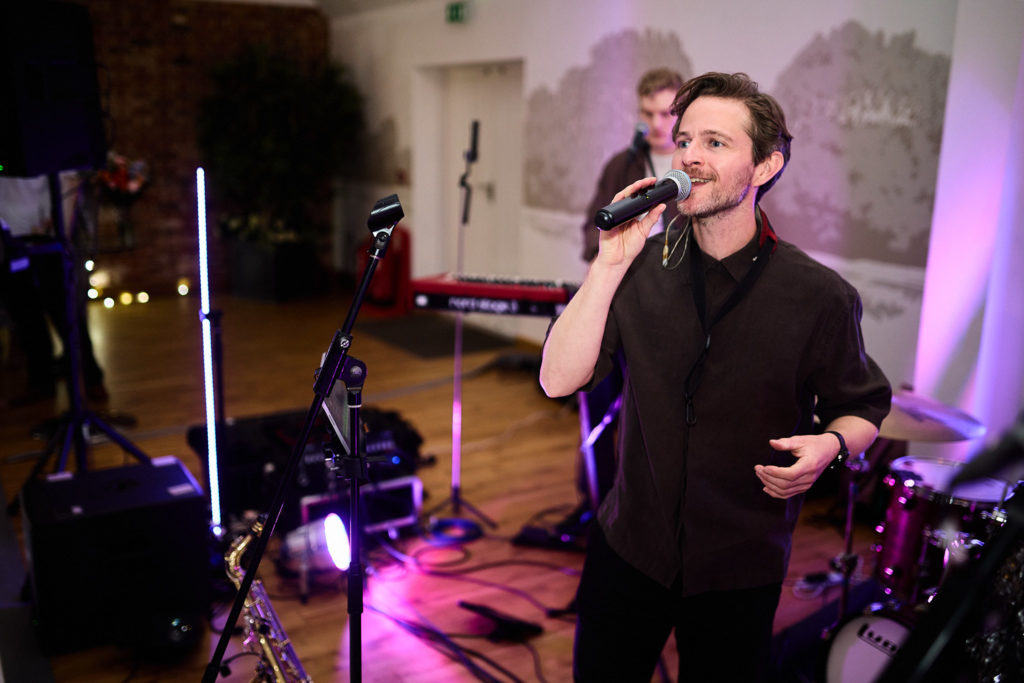 Singer performing with the wedding band under purple lights