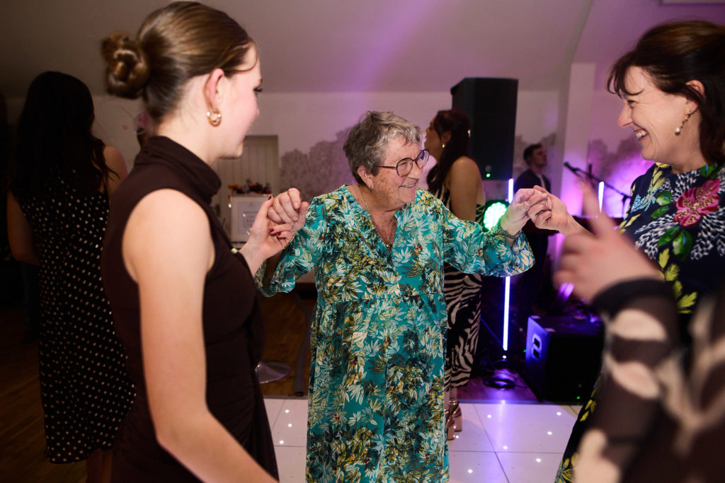 Older guest in a green dress dancing with younger guests