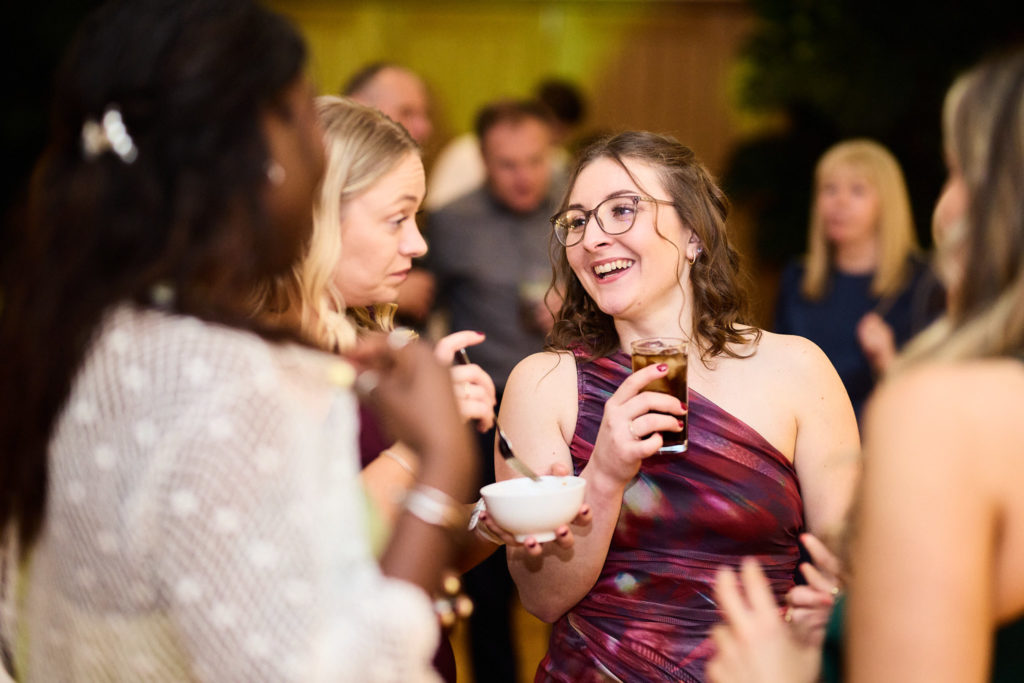 Wedding guests laughing with drinks in the evening