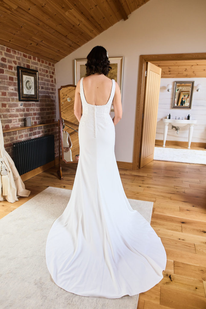 Bride from behind, showing the low back and train of her wedding dress