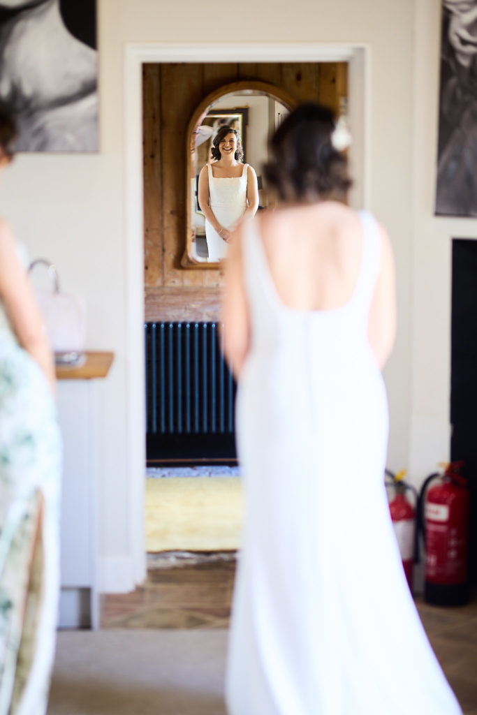 Bride from behind walking towards a mirror in her wedding dress