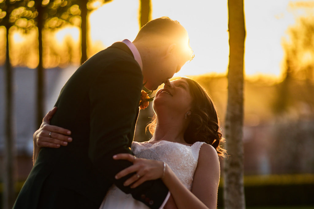 Groom dipping the bride in silhouette against the sunset at Hatfield Place