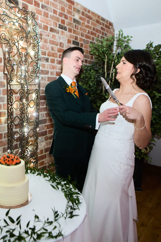Bride and groom laughing as they hold the knife to cut their wedding cake