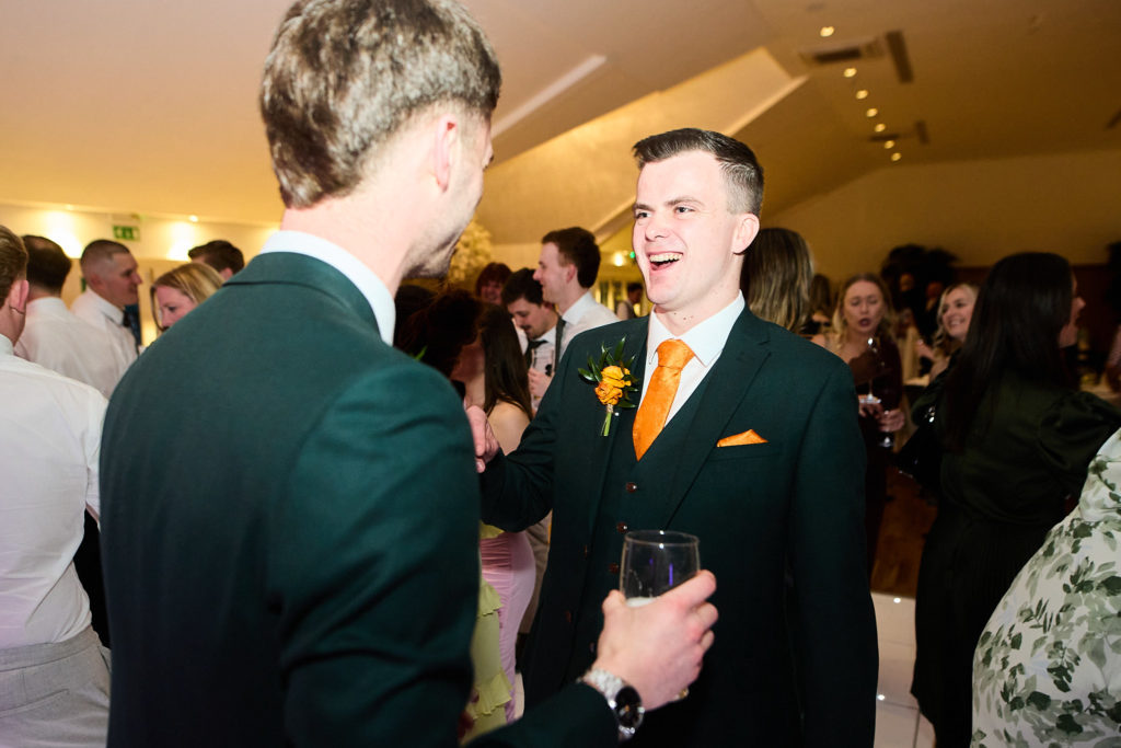 Groom laughing with guests at the evening reception