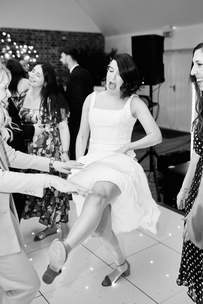 Black and white photo of the bride kicking up her leg on the dance floor
