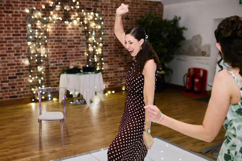 Guest in a polka dot dress dancing with her arm raised