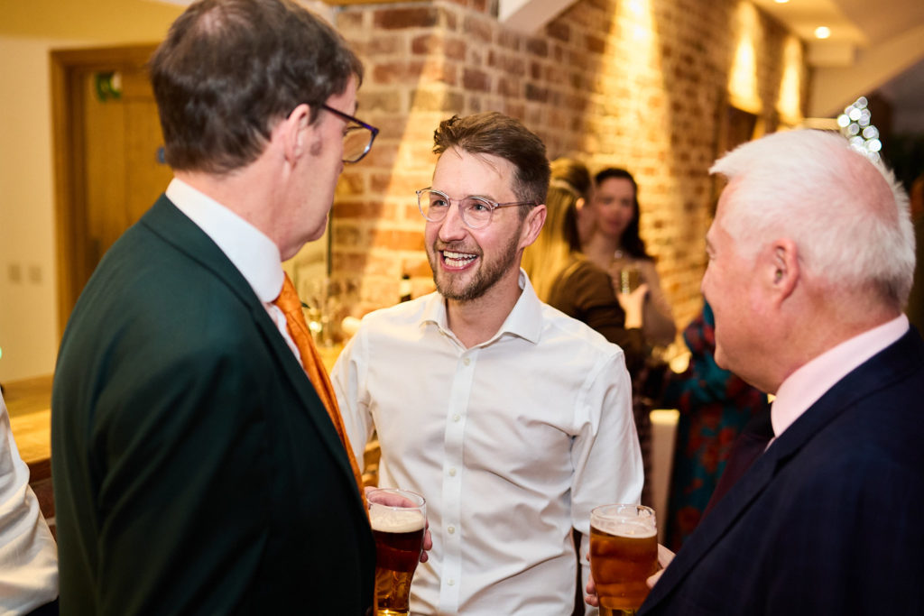 Three men chatting with drinks at the evening reception