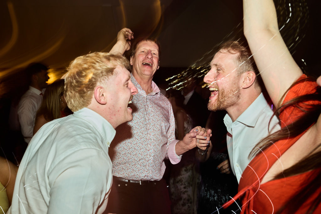 Wedding guests singing with their arms round each other