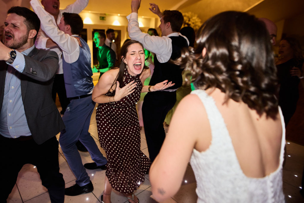 Wedding guests dancing, with the bride seen from behind