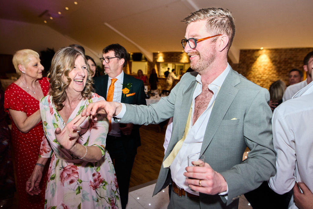 Guest in a pale green suit dancing with a woman in a floral dress