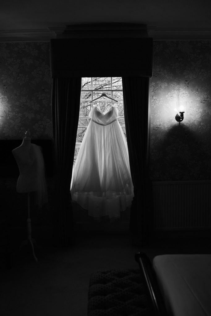 Black and white photo of the wedding dress hanging in a window