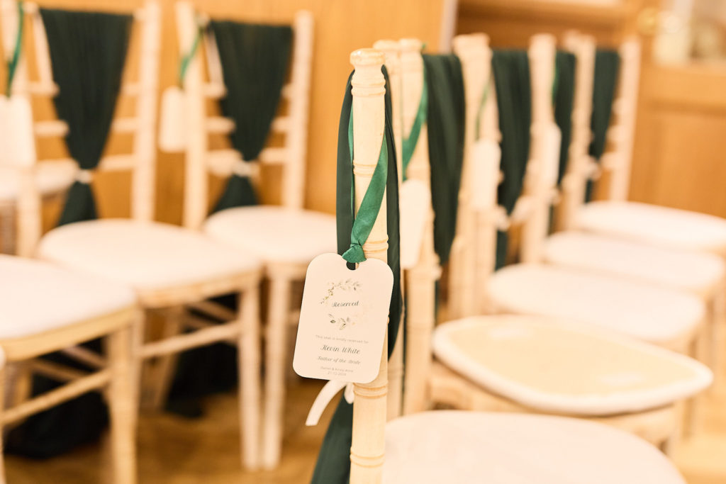 Ceremony chairs tied with dark green sashes and luggage tags