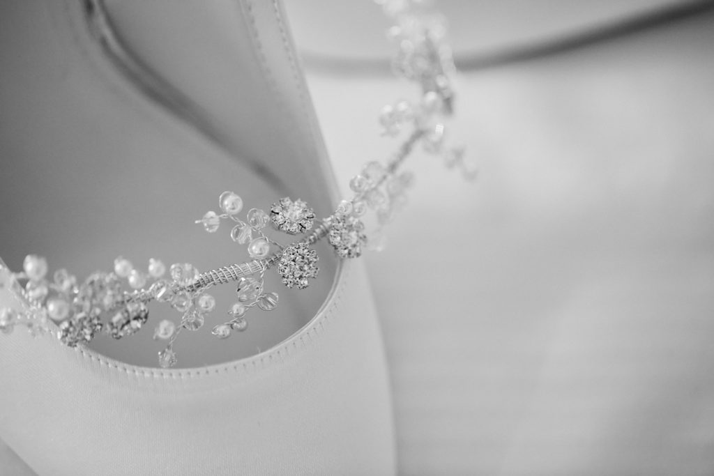 Black and white close-up of a jewelled hair vine on the wedding dress