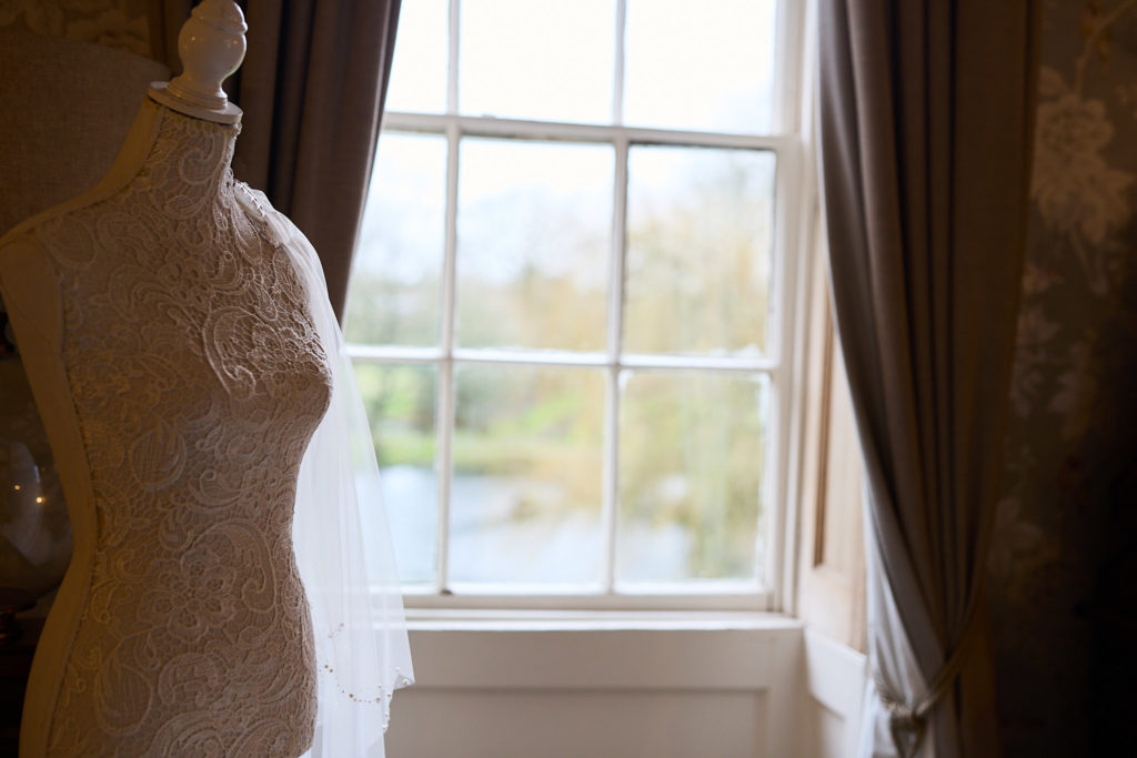 Lace wedding dress on a mannequin beside a sash window