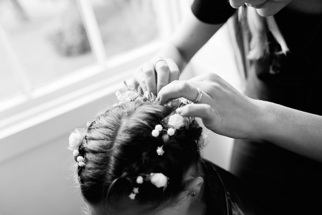 Black and white close-up of flowers being pinned into the bride's hair
