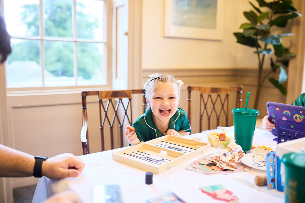 Young girl laughing at a table of crafts on the wedding morning