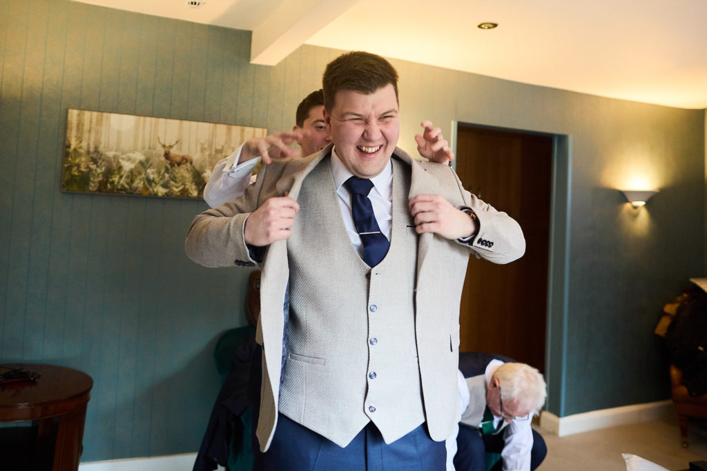 Groom adjusting his waistcoat and tie as he gets ready
