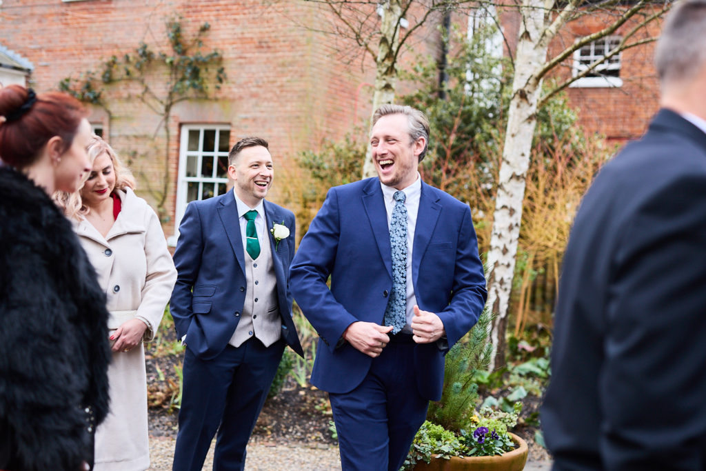Groom laughing with guests in the courtyard at Mulberry House