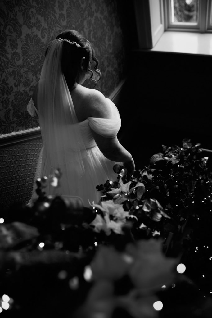 Black and white photo of the bride going down a staircase decorated for Christmas