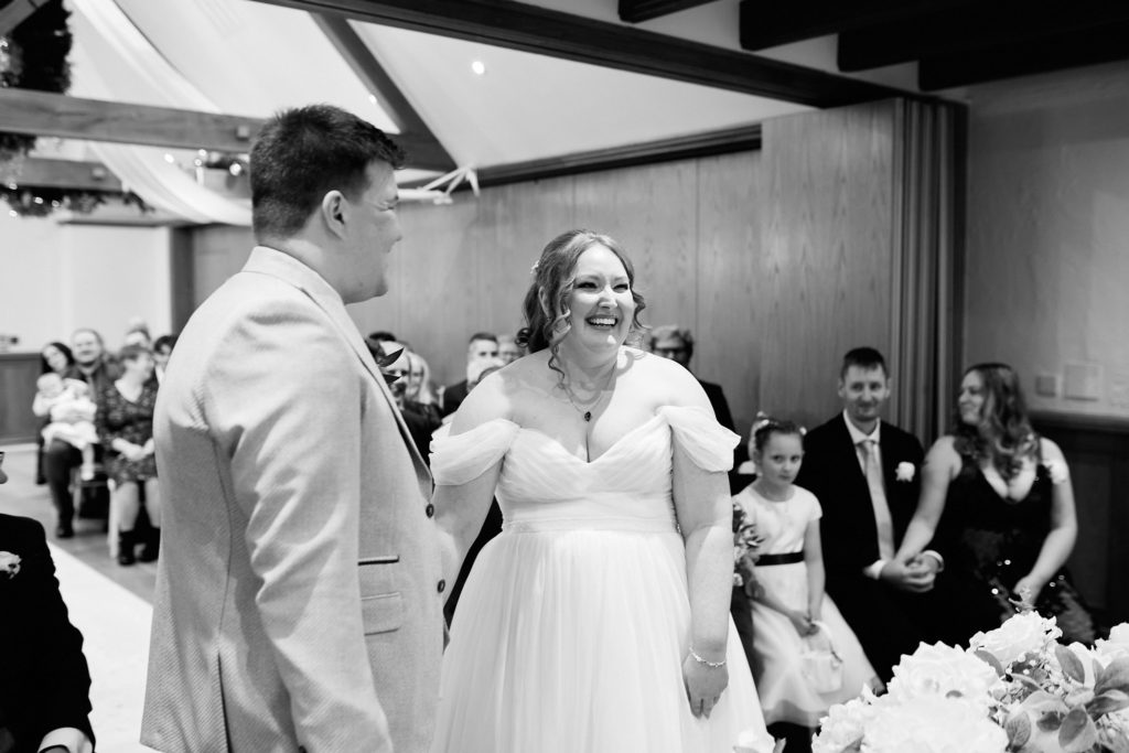Black and white photo of the bride laughing as she joins the groom for the ceremony