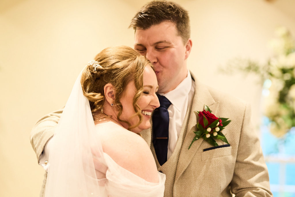 Groom kissing the bride's forehead during the wedding ceremony