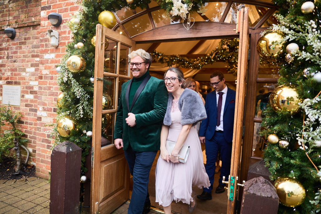 Wedding guests arriving through a doorway trimmed with Christmas garlands