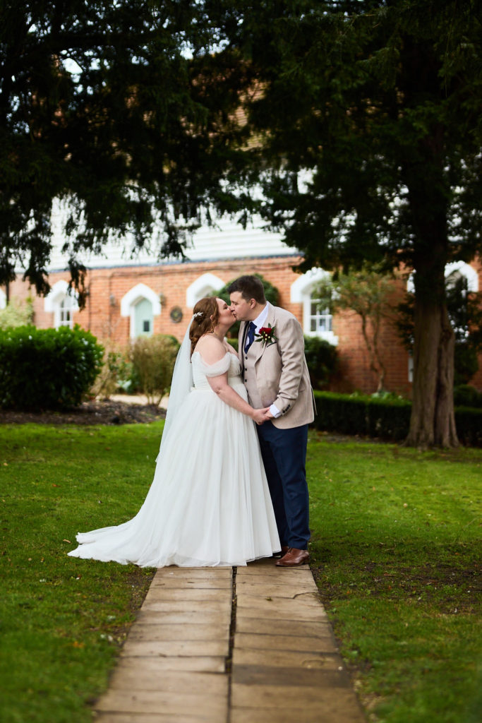 Bride and groom forehead to forehead on the garden path at Mulberry House
