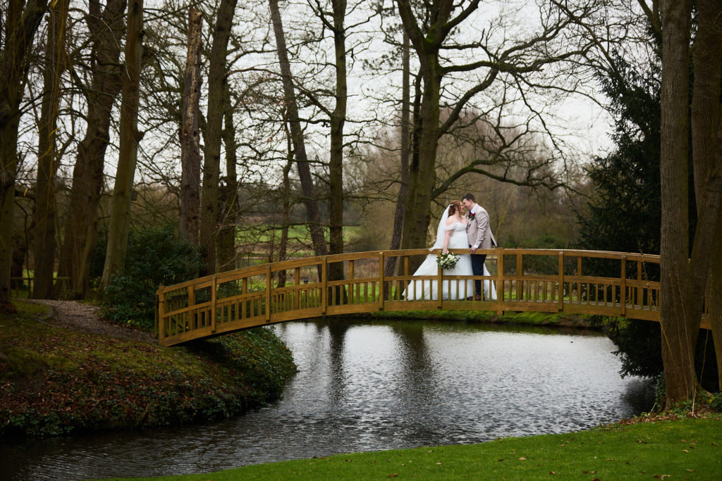 Bride and groom on the wooden bridge over the lake at Mulberry House
