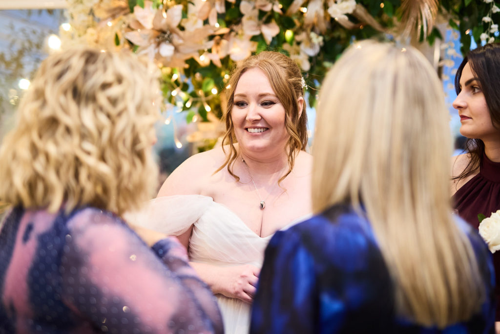 Bride laughing with guests under a canopy of flowers