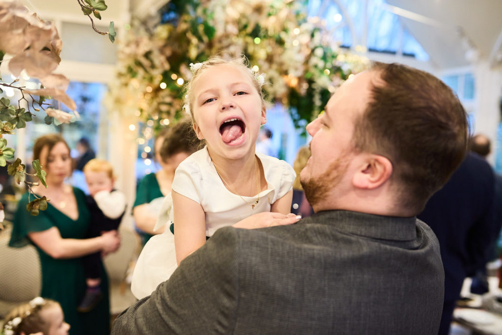 Young girl pulling a face on a man's shoulder at the reception