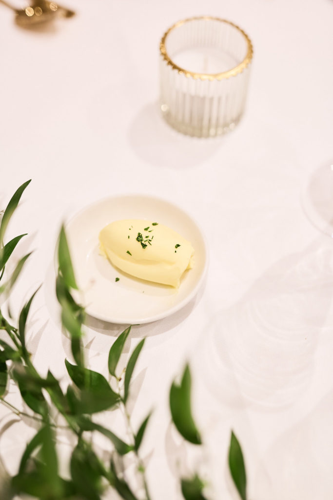 Butter dish and candle on a white tablecloth with green foliage