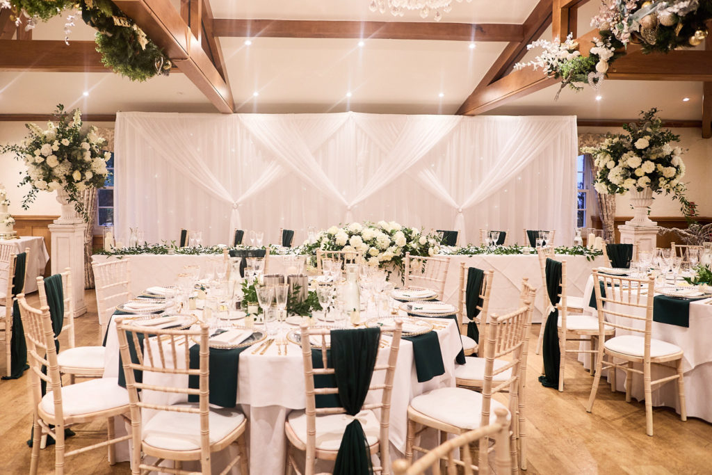 Reception room set with round tables, white flowers and dark green sashes at Mulberry House