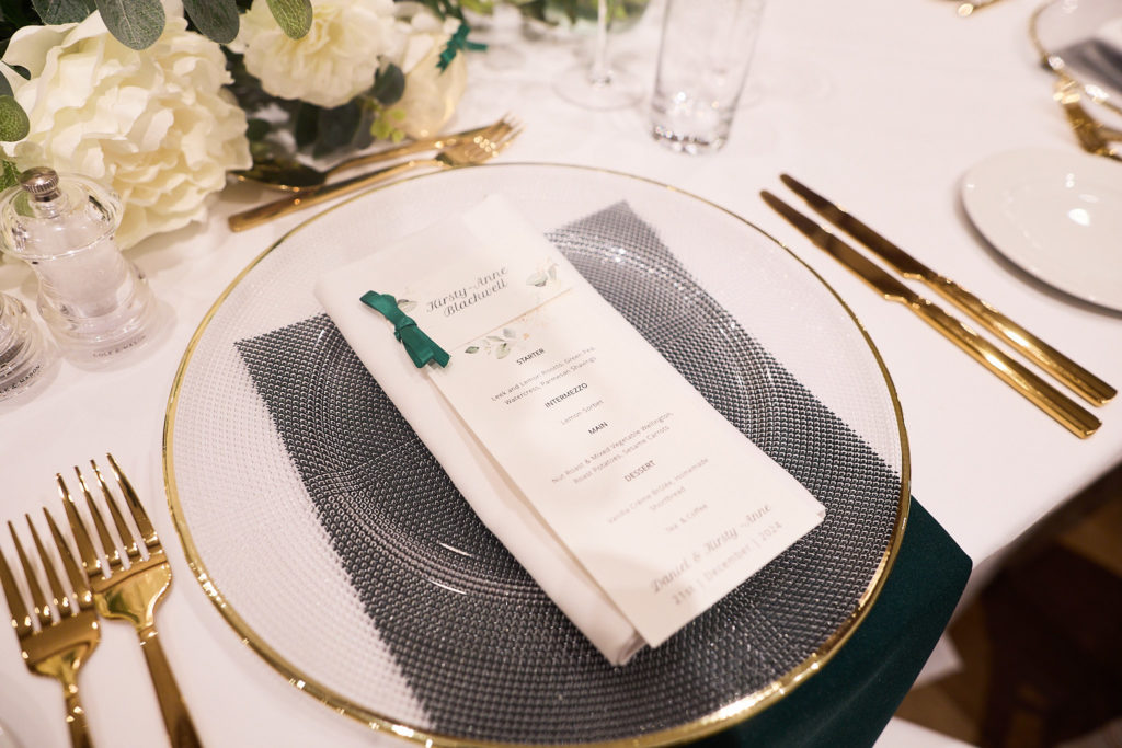 Place setting with a menu card, green napkin and gold cutlery