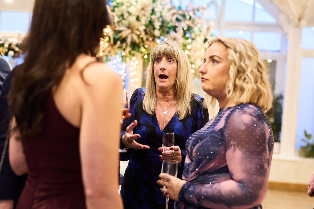 Wedding guests chatting with drinks under hanging flowers