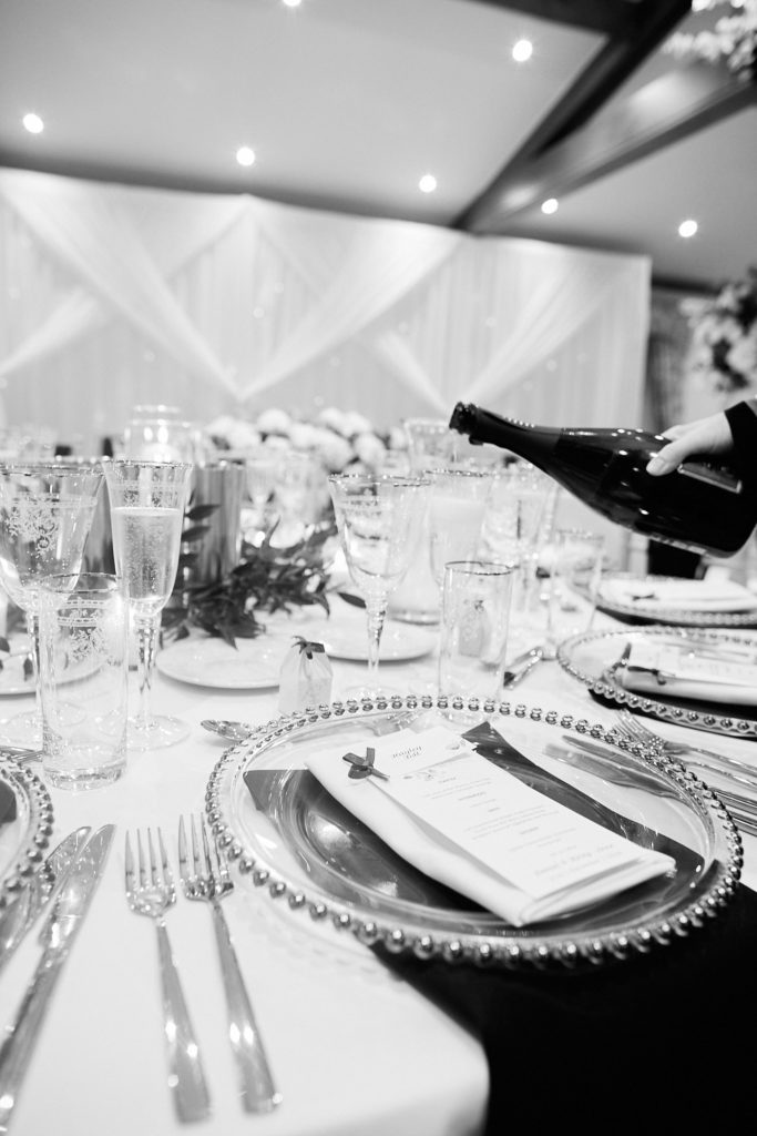 Black and white photo of champagne being poured at a wedding table