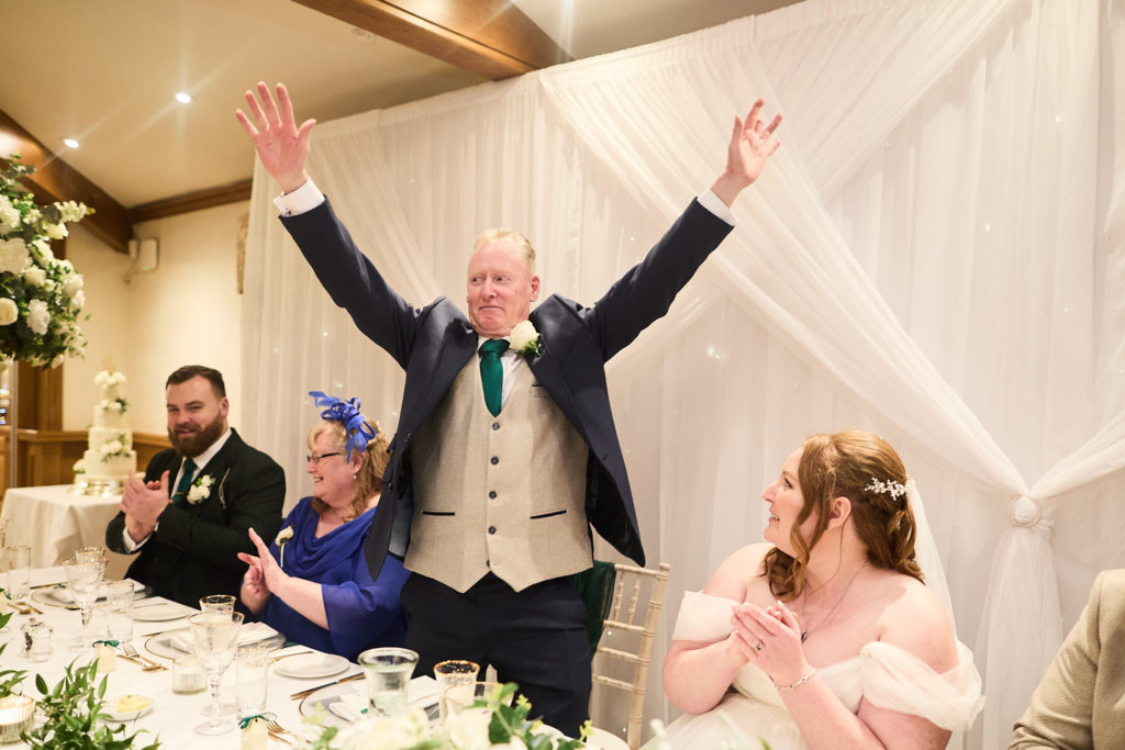 Man in a tartan waistcoat cheering with both arms in the air during the speeches
