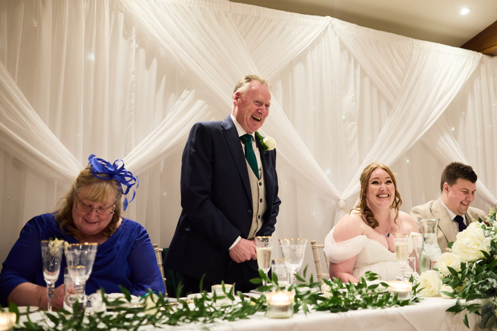 Man in a tartan tie giving a speech at the top table