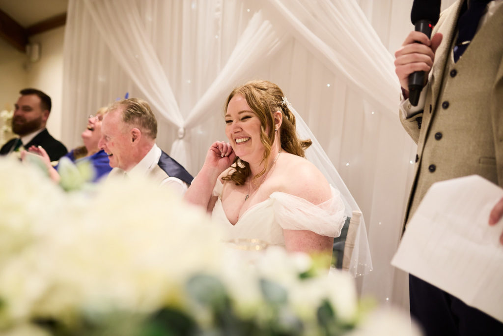 Bride laughing at the top table during the speeches