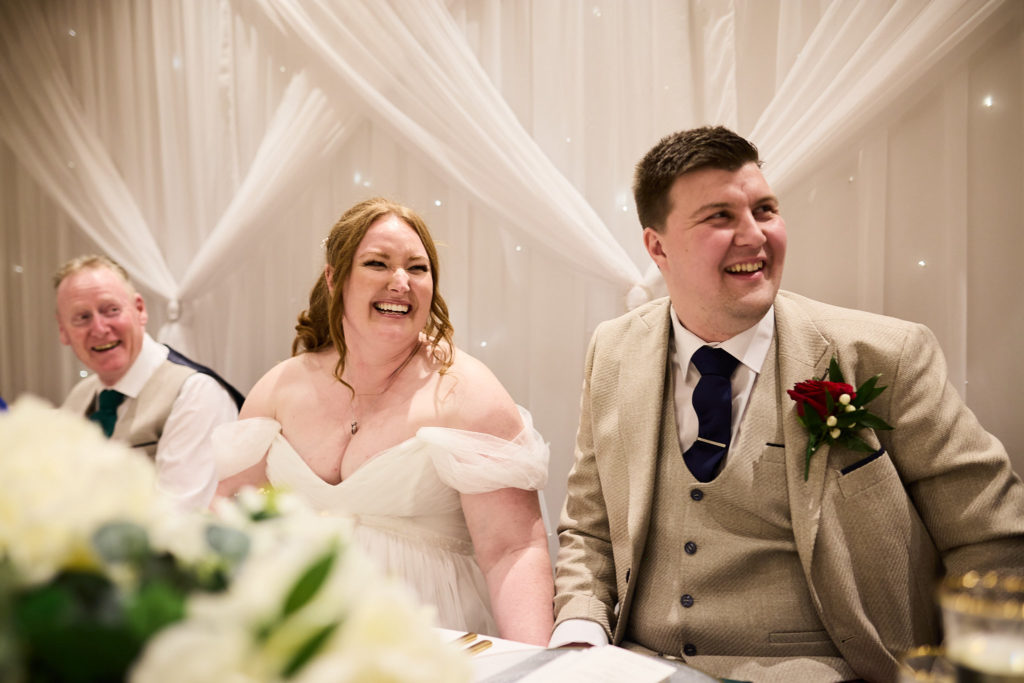Bride and groom laughing at the top table during the speeches