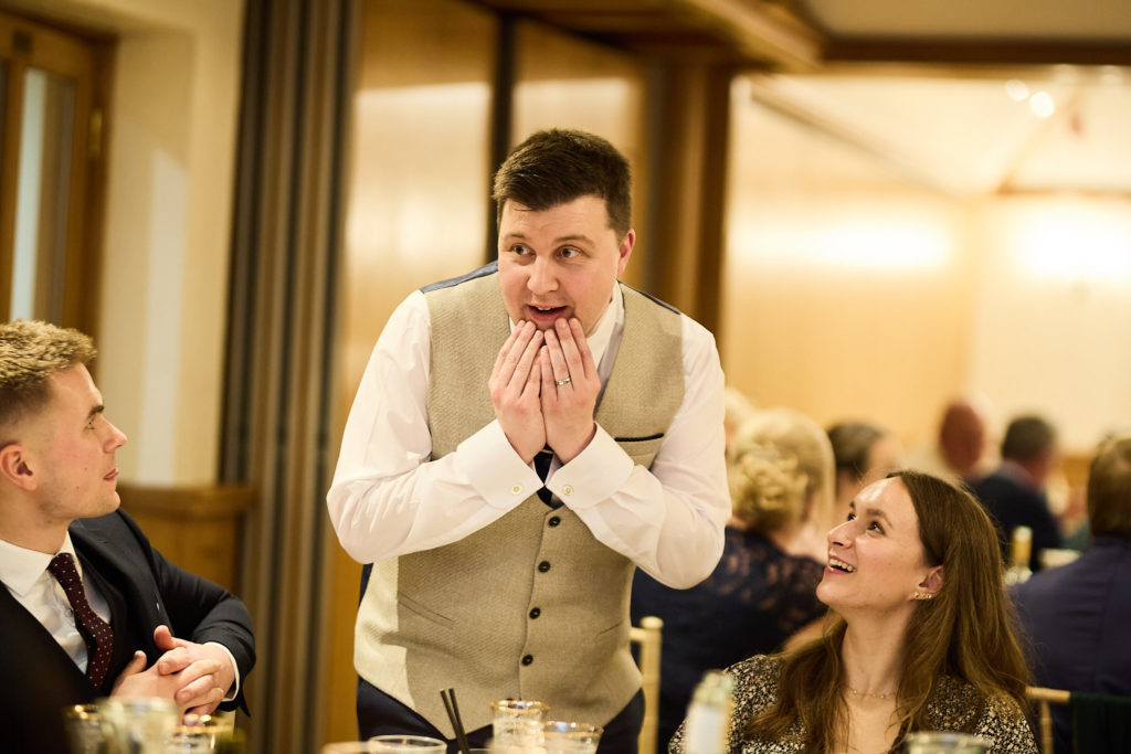 Groom with his hands to his face in surprise among his guests