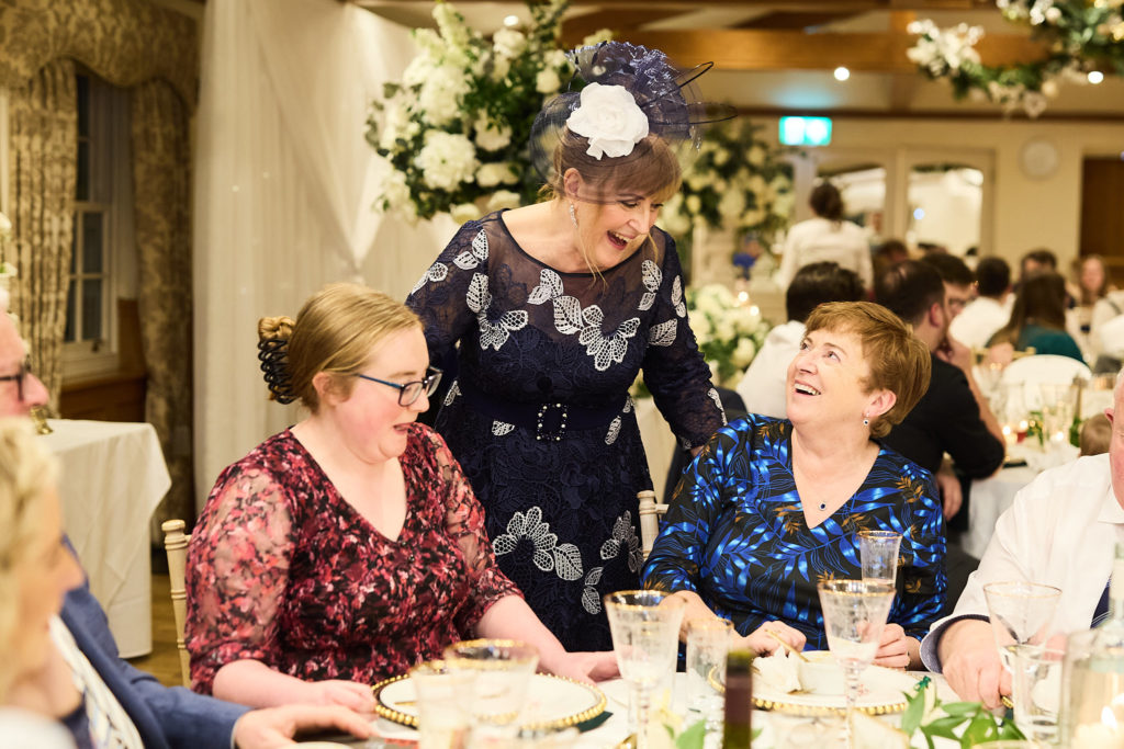 Wedding guests chatting at the table, one in a blue fascinator