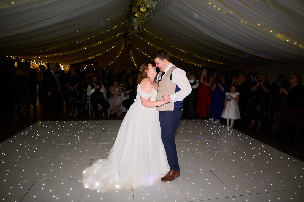 Bride and groom kissing during their first dance in the marquee at Mulberry House