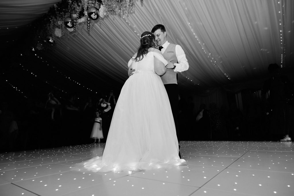 Black and white photo of the bride and groom's first dance on a starlit dance floor